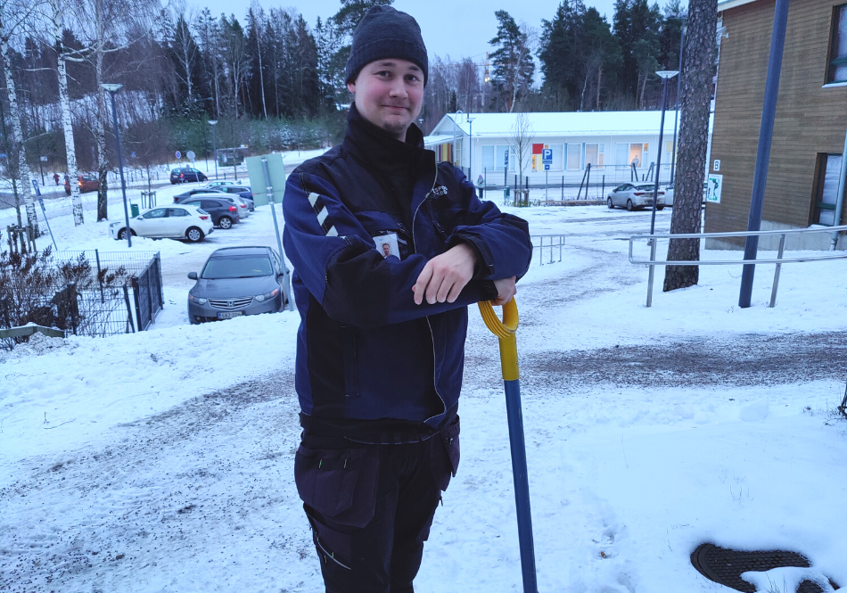 Jesse Turunen seisoo lumilapiota vasten. Taustalla on luminen maisema.