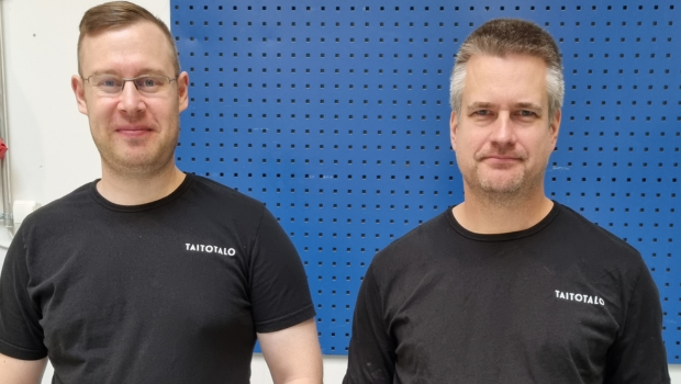 Heikki Marjamaa ja Olli Ringvalla seisovat luokkatilan sinistä seinää vasten. Molemmilla on päällään musta t-paita.