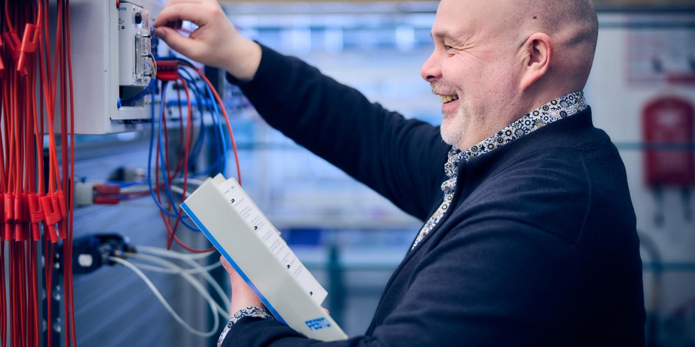 Mies harjoittelee kytkentää pneumatiikkalaitteistolla