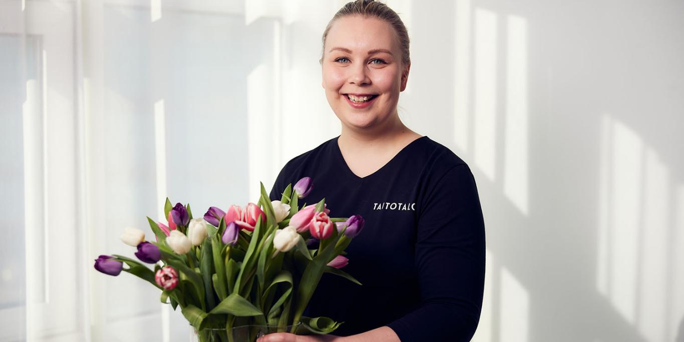 Hymyilevä nainen tulppaanikimpun kanssa