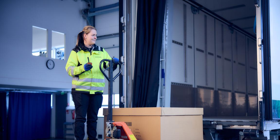 Nainen pumppukärryn kanssa rekan perälaudalla