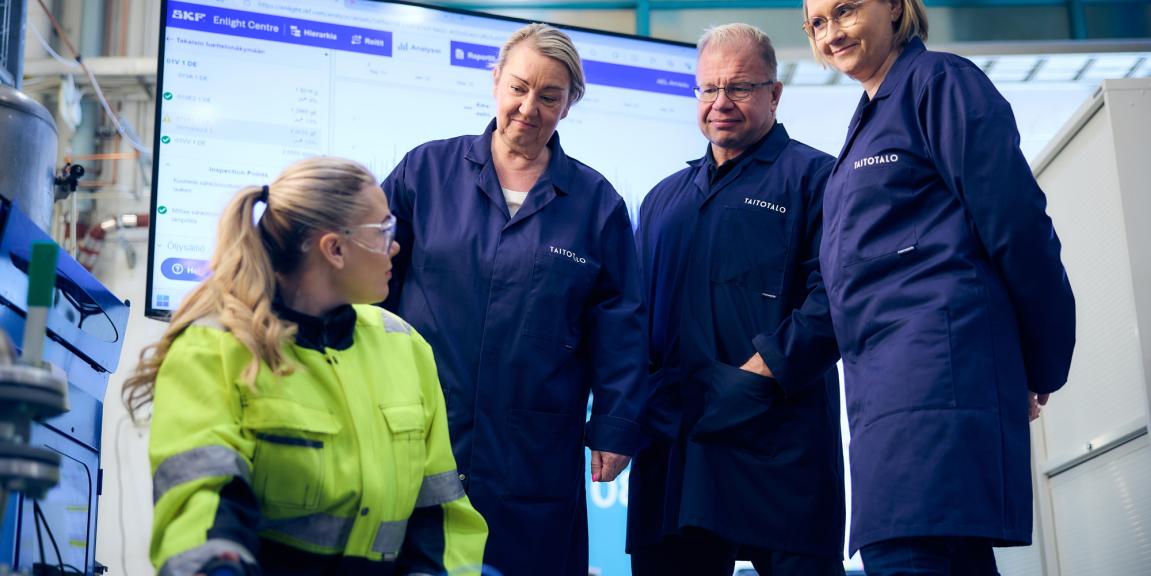 Työtakkinen nainen esittelee teollisuuspumppua kolmelle opiskelijalle