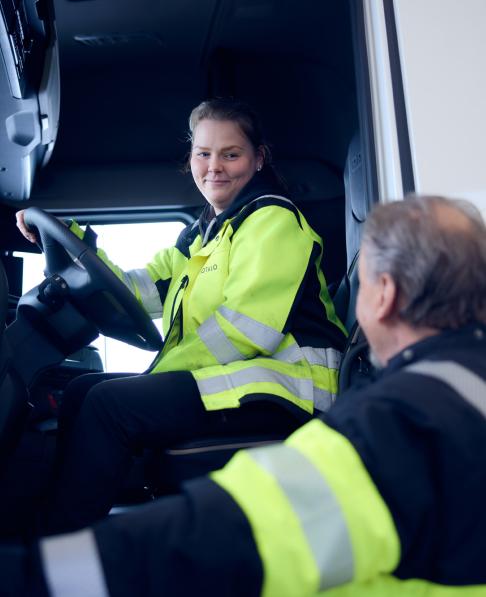 Kouluttaja neuvoo opiskelijaa rekan ohjaamossa