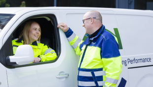 Kaksi Caverionin kylmäasentajaa työvaatteissa. Toinen asentaja istuu pakettiautossa kuljettajanpaikalla ja toinen seisoo auton vieressä. Asentajat juttelevat keskenään ja pakettiauton ikkuna on auki.