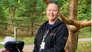 Kati Lehtinen-Bennett  seisoo metsämiljöön edessä.